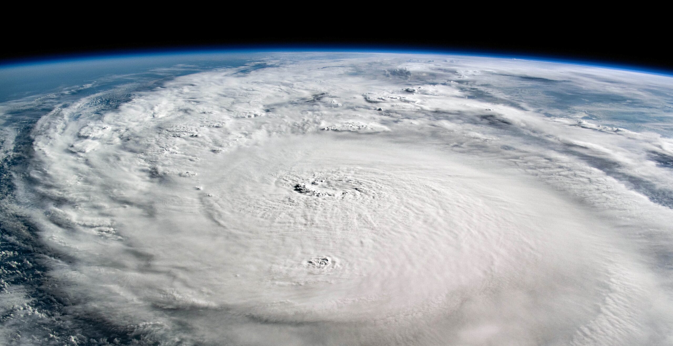 A satellite photo of Hurricane Milton as a massive swirling mass of white cloud above earth with black space at the top of the photo.