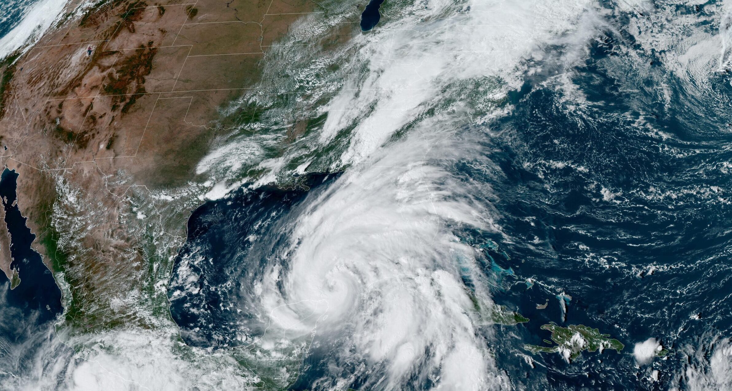 A satellite image of Hurricane Helene in the Gullf of Mexico. The hurricane is a massive swirl of white cloud with the grey and brown landmass of Mexico and the US to the left.