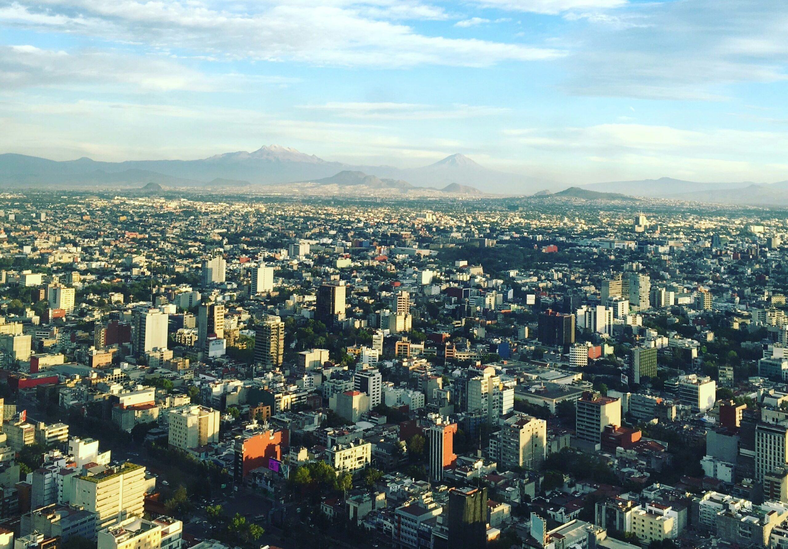 An aerial photo of Mexico city with dense buildings and mountains in the background